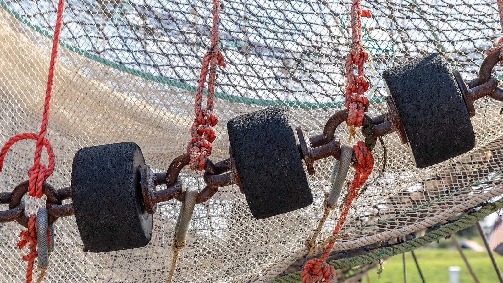 Detail of a trawl net, float line and chain on a quayside